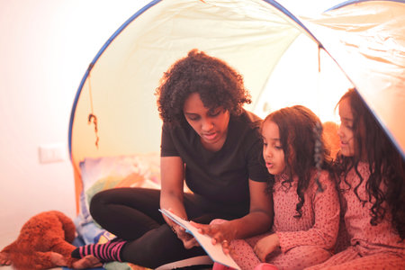 family under a tent in the house reads a book