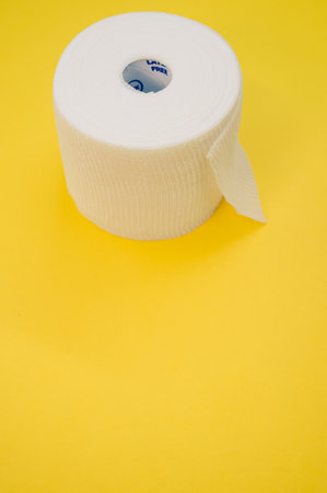 a vertical shot of a sterile gauze bandage roll isolated on a yellow backgroundの写真素材