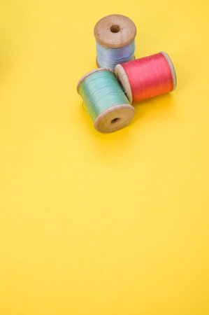 A colorful sewing threads isolated on a yellow background with free space for textの写真素材