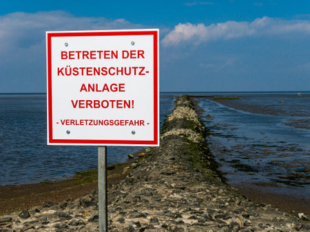 A red/white sign in german saying Do not enter the coastal protection system. Standing on the...