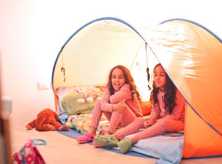 two sisters in a camping tent at homeの写真素材