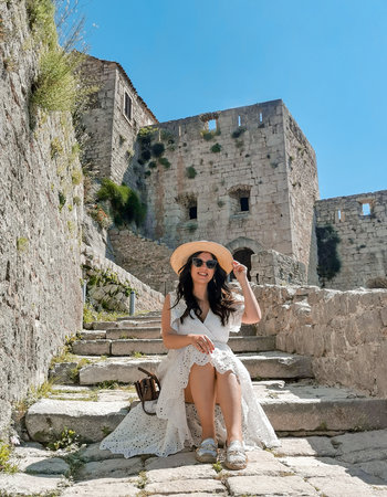 Beautiful young woman wearing long white summer dress and sun hat on a hot sunny day.の写真素材