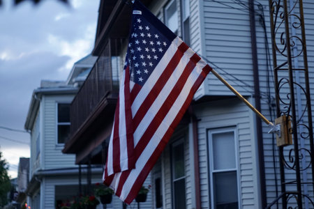 A selective focus of the American National flag on a metal structure against blurred old houses