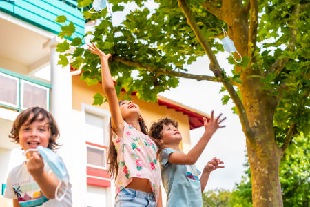 Children in a park pulling up the surgical mask at the end of the coronavirus pandemic. End of restrictions abroad, happy to be able to breathe well again, covid19の写真素材