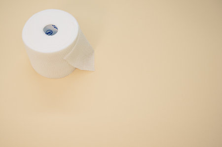 a top view of a sterile gauze bandage roll isolated on a light beige background on the left sideの写真素材