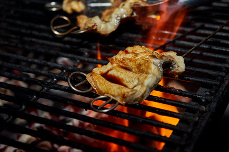 A closeup shot of fresh Japanese marinated eel on a skewer being grilledの写真素材