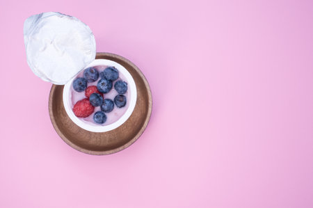 A top view of a berry yogurt in a plastic cup on a pink backgroundの写真素材