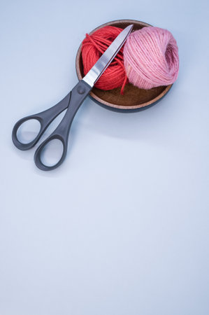 A vertical shot of scissors and cotton yarn on a blue surface - copy spaceの写真素材
