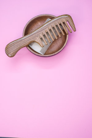A closeup shot of scissors and hair comb on a pink surface - copy space