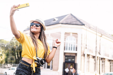 cheerful and smiling Hispanic woman photographer tourist taking a picture on the street. travel...