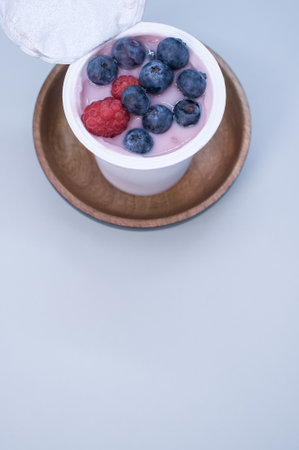 A top view of a berry yogurt in a plastic cup on a blue backgroundの写真素材