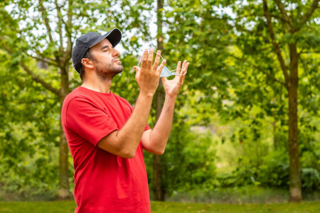 A young man in a red shirt celebrating the end of the coronavirus pandemic restrictions by removing...