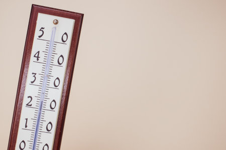 a closeup of a room thermometer isolated on the light beige background on the left sideの写真素材