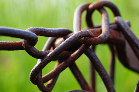 Close-up of an old rusty barrier chain. Macro shot with green bokeh.