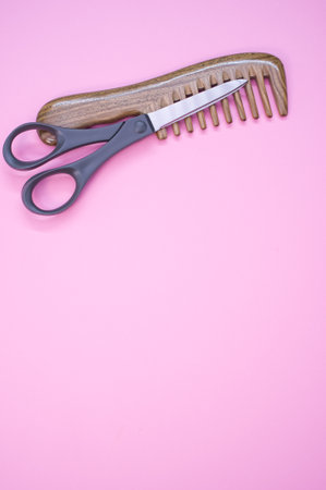 A vertical shot of a hairbrush and scissors on a pink backgroundの写真素材