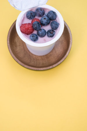 A top view of a berry yogurt in a plastic cup on a yellow backgroundの写真素材