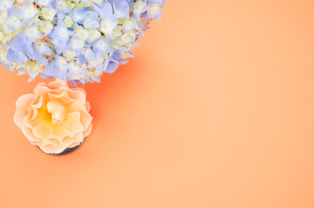 A closeup shot of blue hydrangea and polymer clay flower isolated on a peach background