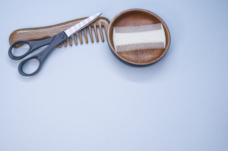 A top view of hairbrushes, scissors, and a wooden bowl on a blue backgroundの写真素材