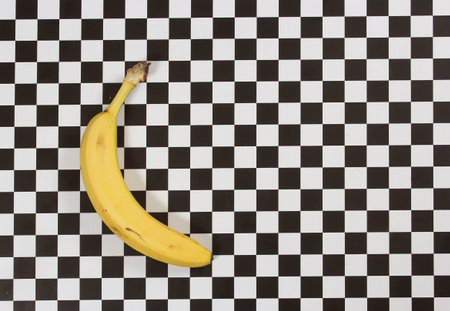 Ripe Banana on Black and White Checkered Tableの写真素材