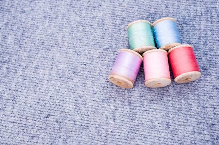 A colorful sewing threads on a grey fabric with free space for textの写真素材