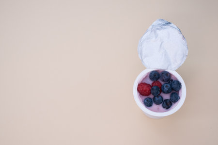 A top view of a berry yogurt in a plastic cup on a beige backgroundの写真素材