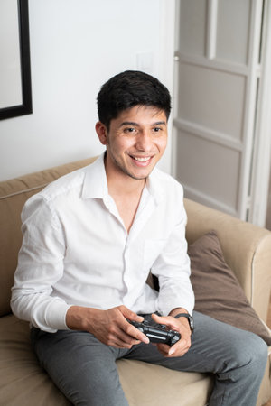 Latin man playing console on sofa