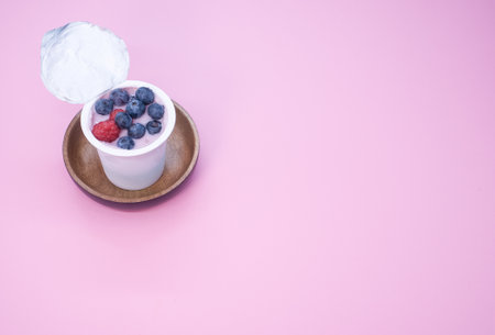 A top view of a berry yogurt in a plastic cup on a pink backgroundの写真素材