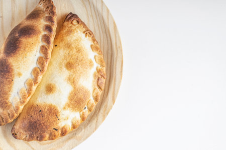 Delicious Argentine empanadas on a wooden board on a white background with space for textの写真素材