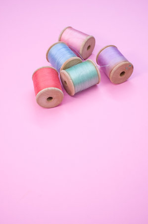 A colorful sewing threads isolated on a pink background with free space for text