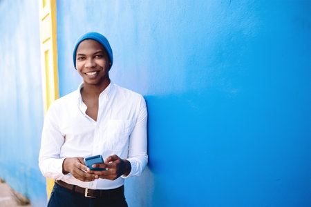 Portrait of a happy and smiling African American man with a phone in his hand looking at the camera. happiness and mobile technology concept.の写真素材