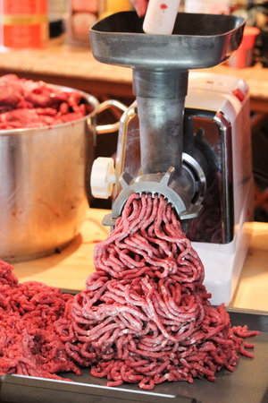 A closeup shot of minced meat coming out of a meat grinder in the kitchenの写真素材