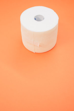 a vertical shot of a sterile gauze bandage roll isolated on a coral backgroundの写真素材