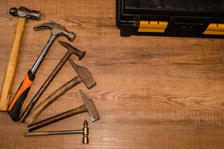 A top view of several types of hammers on a wooden table