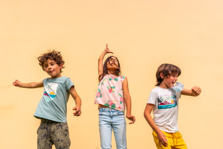 Children celebrating the end of the coronavirus pandemic the mask pulling the surgical one. End of restrictions abroad, happy to be able to breathe well again, covid19, yellow backgroundの写真素材