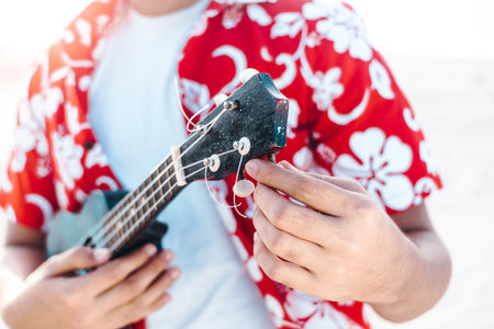 hands of a person holding and tuning a string instrument or ukulele. music and learning concept....