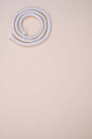A vertical shot of a rope on a beig surface - copy space