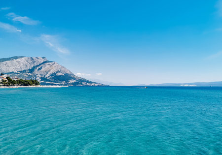 Clear skies above beautiful blue and azul colored sea on adriatic coast in Omis in Croatia. Amazing coastline with mountainの写真素材