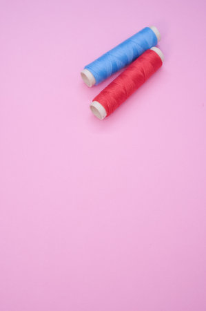 A closeup of the colorful sewing threads on the pink surface - space for textの写真素材