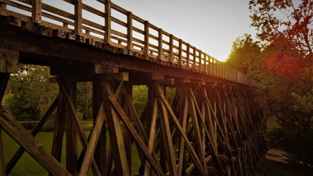 A side view of a wooden trestle narrow footbridge at sunsetの写真素材