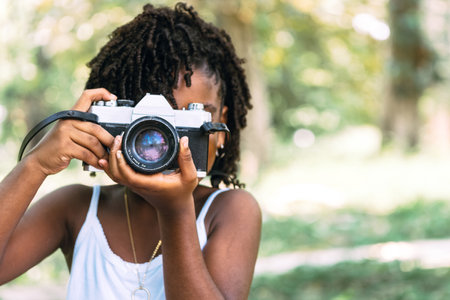 portrait of a small young African girl holding a camera and taking a photo. fun and childhood conceptの写真素材