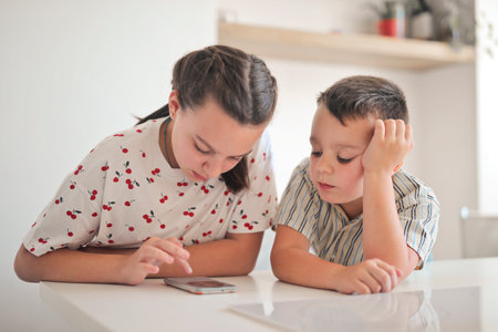 two children use a smartphone in the kitchen