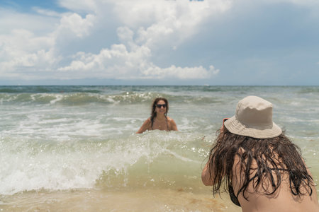 Daughter photographing her mother at the beachの写真素材