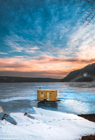 An old cabin house in the middle of a frozen lakeの写真素材