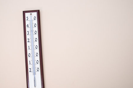 a closeup of a room thermometer isolated on the light beige background on the left sideの写真素材