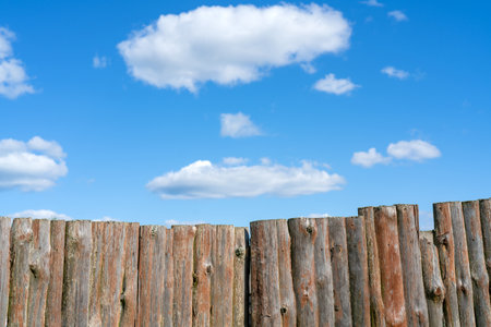 An aged wooden log fence under a bright blue skyの写真素材