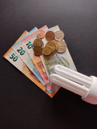The closeup of compact fluorescent lamp on euro coins and banknotes