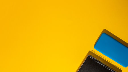 A top view of a smartphone and a notepad on a yellow backgroundの写真素材