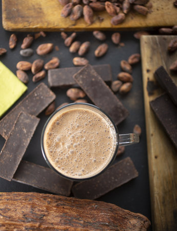 A vertical shot of delicious coffee, coffee beans, and dark chocolate bars