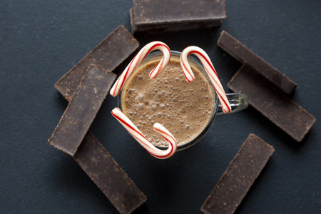 A top view of coffee with candy canes and dark chocolate bars on a bla backgroundの写真素材
