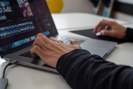 A person editing videos and photos on his laptop in his houseの写真素材